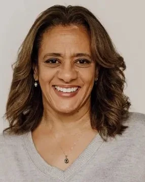 Kim Griffiths, smiling, in a light grey V-neck sweater.