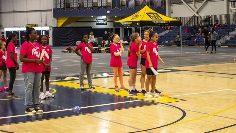 Young athletes and coaches on a gymnasium court during a clinic.