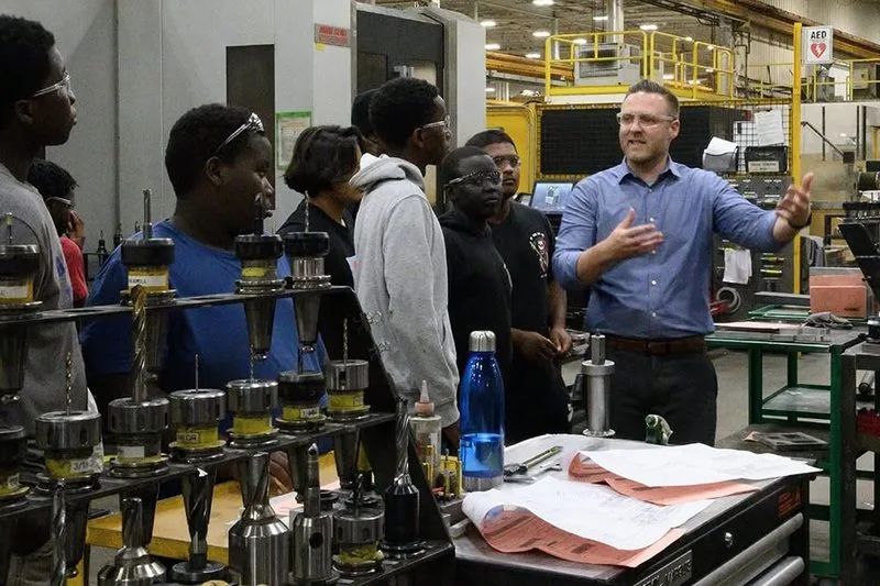 Young people touring a trades workshop with an instructor.