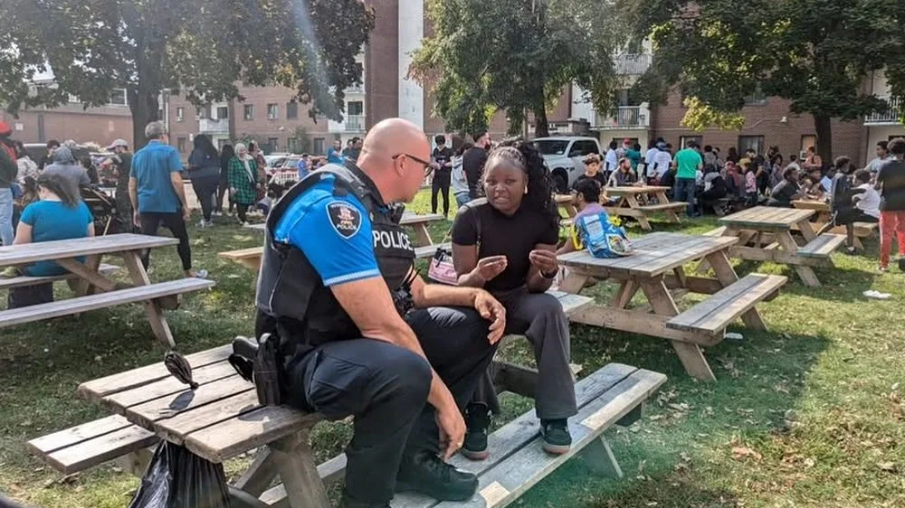 A police officer and a young woman talking at a picnic table during an outdoor community day.