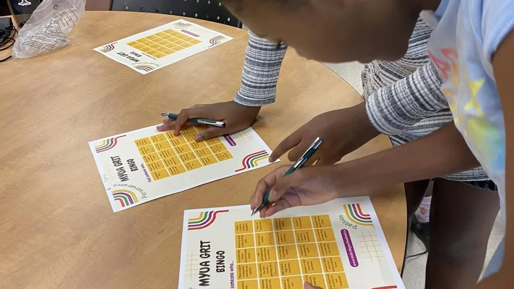 A young person working through a printed activity sheet at a table during a mentorship session.