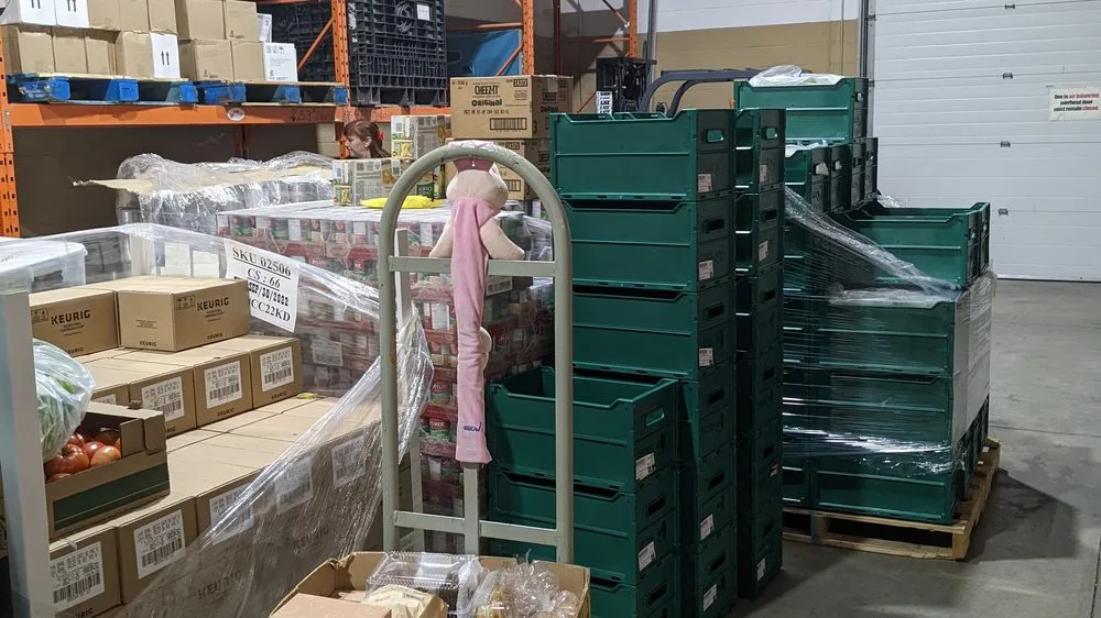 Pallets of boxed food and stacked crates in a partner organization's storage room.