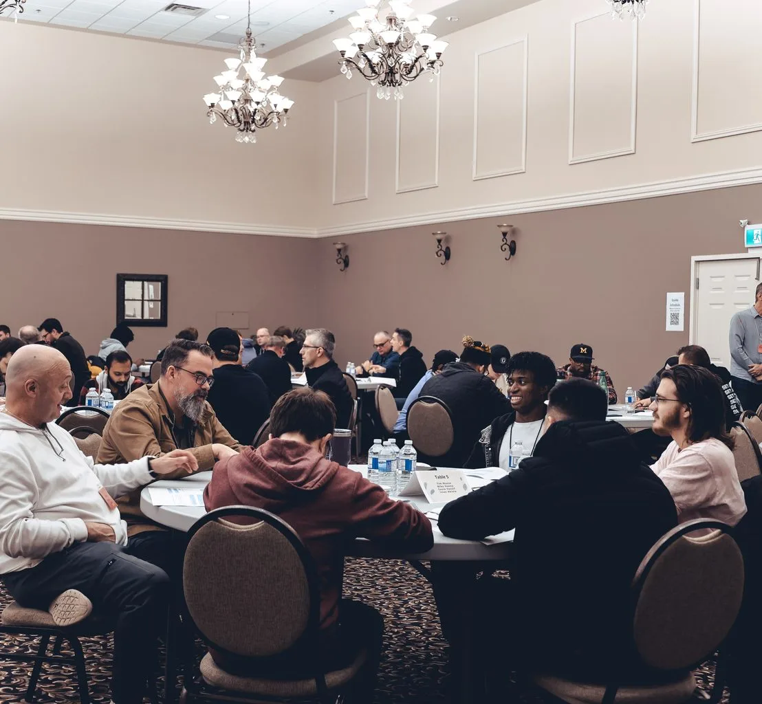Participants seated at round tables through a full room during a leadership training day.