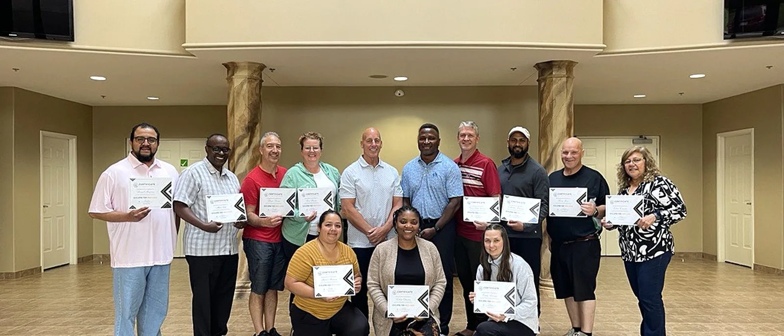 A leadership cohort standing together with their certificates at the end of a course.